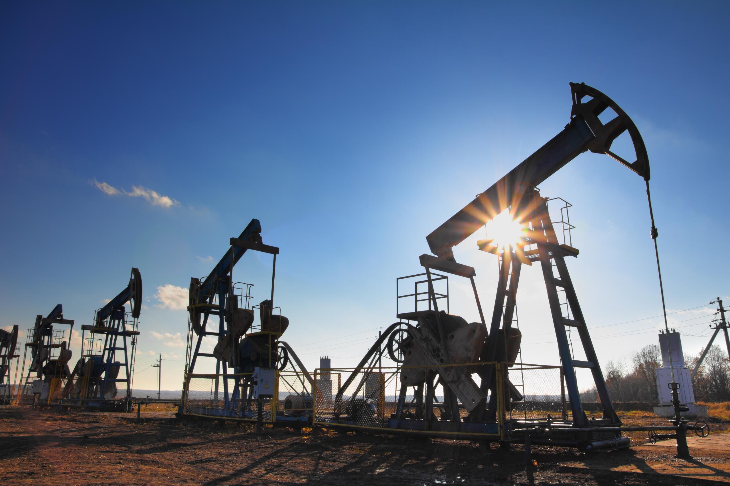working oil pumps silhouette against sun
